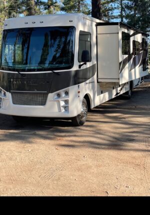 A white and black rv parked in the sun.