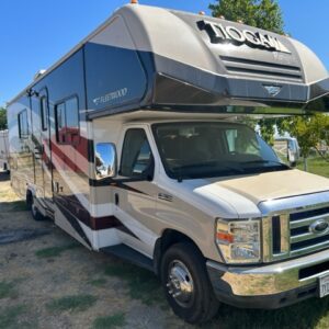 A white and black rv parked in the grass.