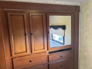 A large wooden cabinet with a mirror on the wall.