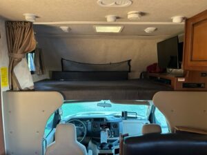 A view of the inside of a car with a couch and television on top.
