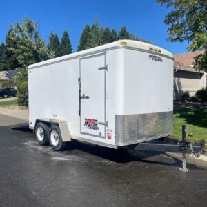 A white trailer parked on the side of a road.