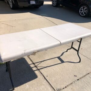 A white folding table sitting on the ground.