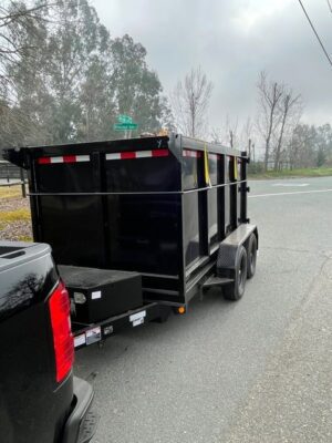 A black dump trailer with the back end pulled up.