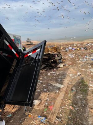 A dump truck is parked in the middle of a garbage pile.