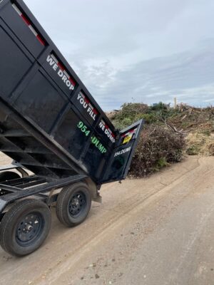 A dump truck is dumping trash on the side of the road.