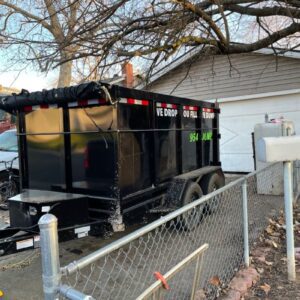 A black trailer with a large dumpster behind it.