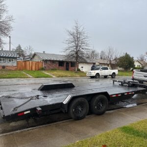 A black trailer is parked on the side of the road.