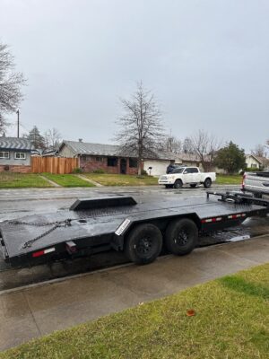 A black trailer is parked on the side of the road.