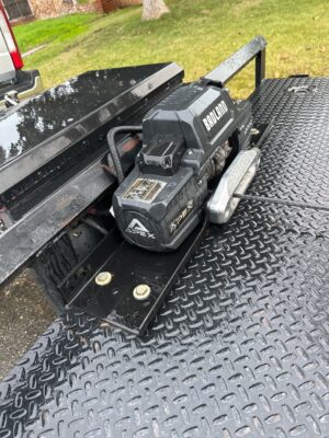 A black truck with a large piece of metal on it's side.