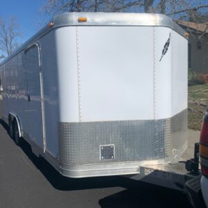 A white trailer parked on the side of a road.