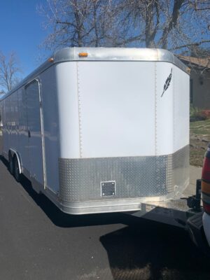 A white trailer parked on the side of a road.