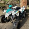 A white and blue atv parked in the dirt.